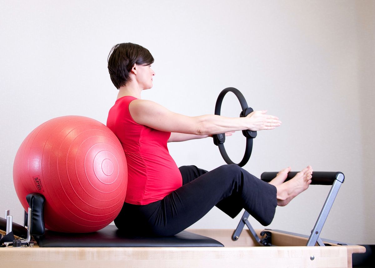 A woman in a red shirt doing Pilates