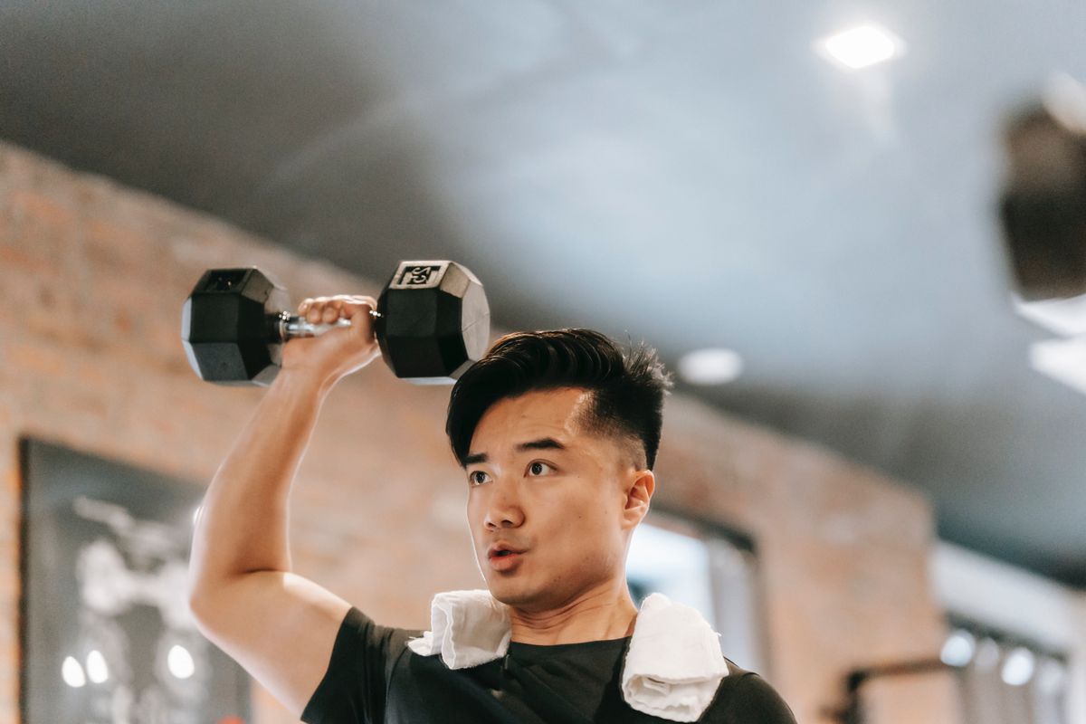 A person in a black shirt lifts a dumbbell overhead