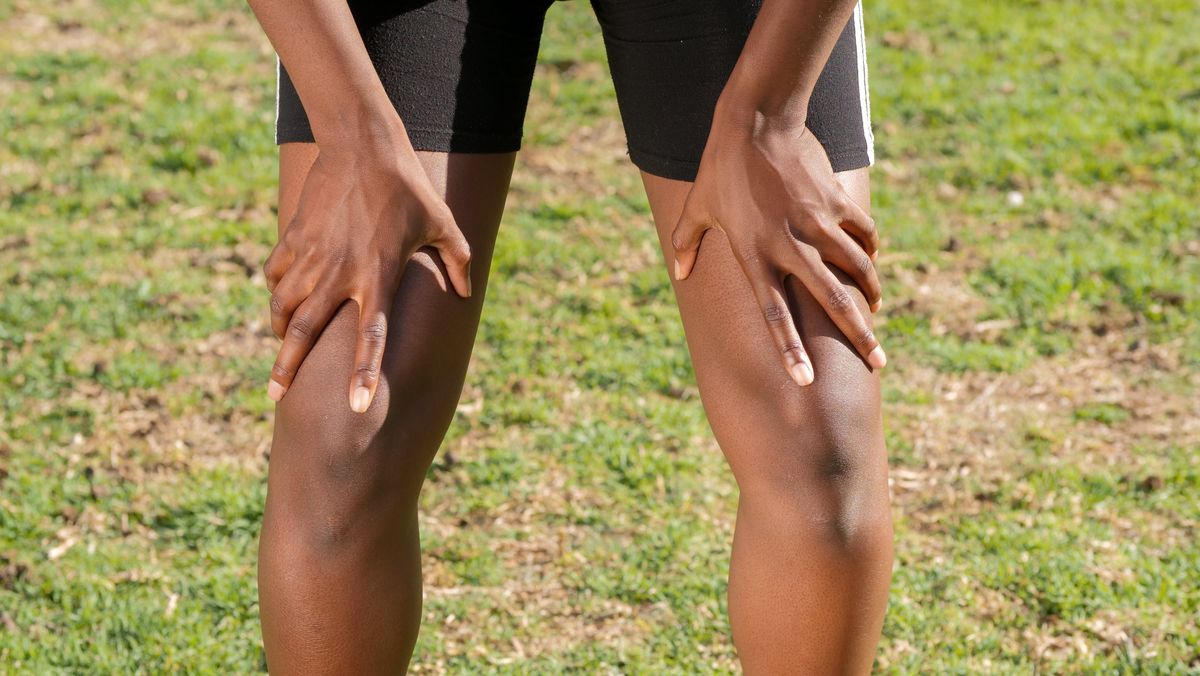 An athlete rests their hands on their knees