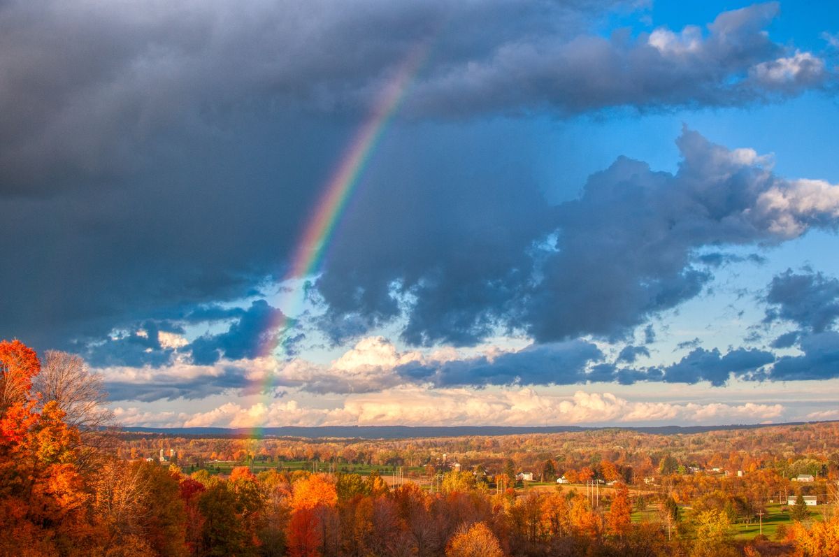 A rainbow above rolling hills in the fall in Pennsylvania