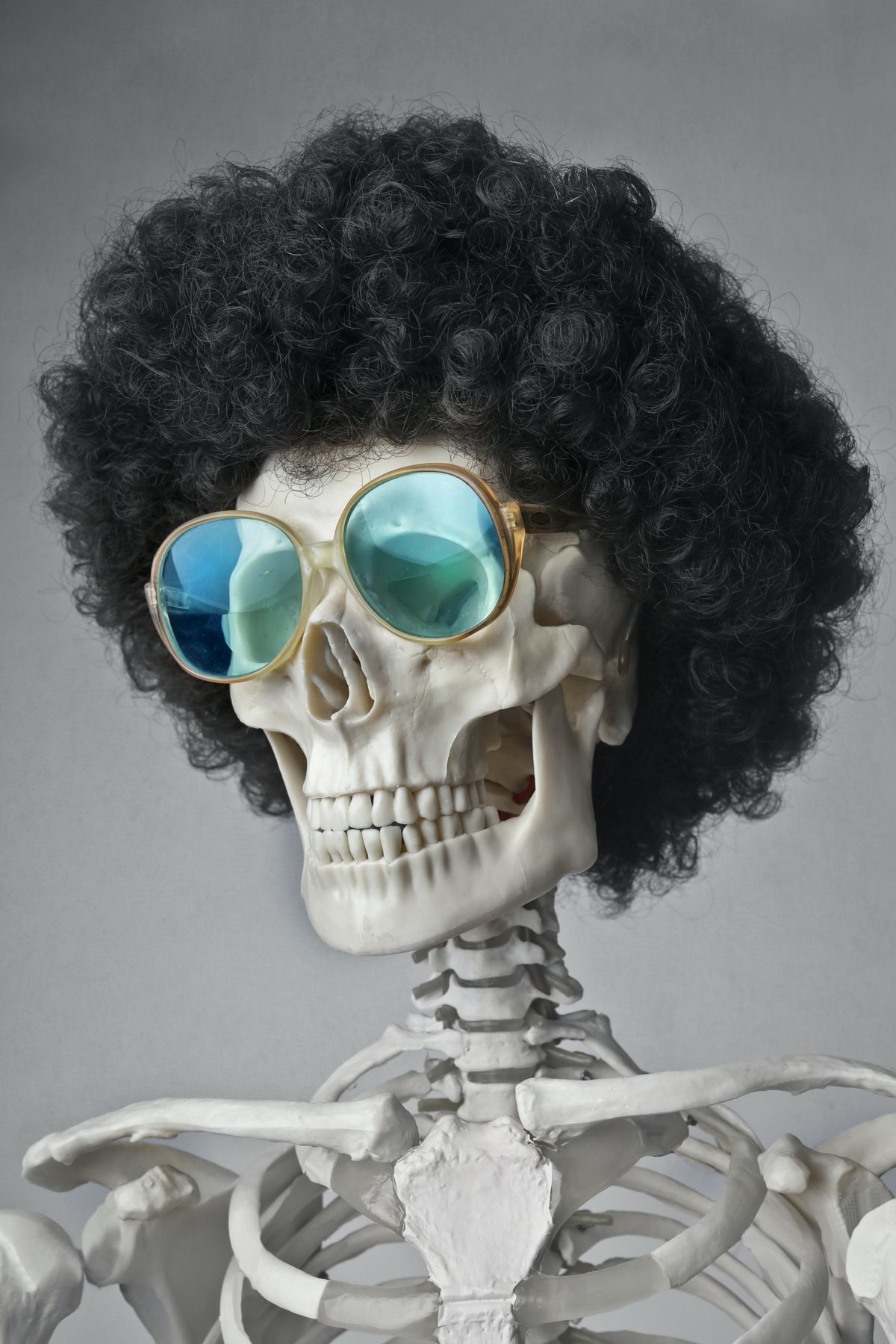 A skeleton wearing an afro wig and 80s glasses.